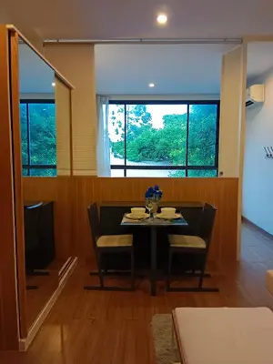 a dining room with a table and chairs and windows at Hill Myna Condotel by Bcare - One Bedroom in Ban Thalat Choeng Thale