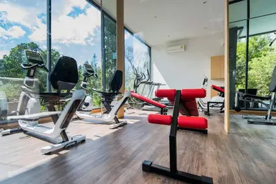 a gym with cardio equipment in a room with windows at Hill Myna Condotel by Bcare - One Bedroom in Ban Thalat Choeng Thale