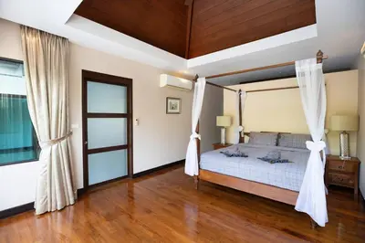 a bedroom with a canopy bed and a wooden floor at Private Pool Villa Nai Harn Beach in Rawai Beach
