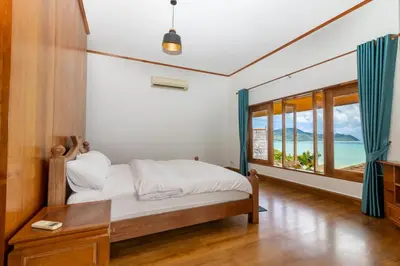 a bedroom with a bed and a table and a window at Aoyon Beach, a 5-bedroom Thai-style villa with stunning sea views, 50 meters direct beach access, free maid, in Phuket Town