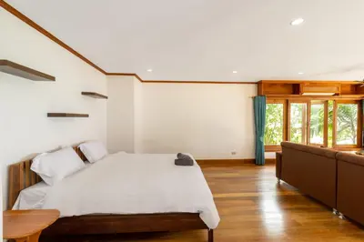 a bedroom with a bed and a wooden floor at Aoyon Beach, a 5-bedroom Thai-style villa with stunning sea views, 50 meters direct beach access, free maid, in Phuket Town