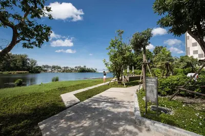 a path next to a lake with a person standing on it at Cassia 1 BR Sea View apt by NLA in Bang Tao Beach