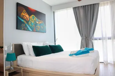 a bedroom with a large bed with white and green pillows at Cassia 1 BR Sea View apt by NLA in Bang Tao Beach