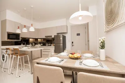 a kitchen with a large wooden table with chairs at Cassia 2 BR Lake&Road View apt by NLA in Bang Tao Beach