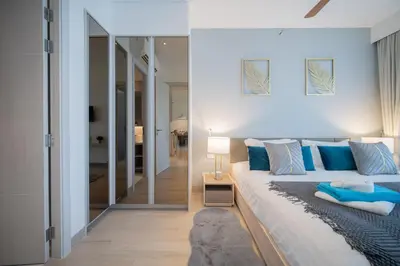 a bedroom with a large bed with blue pillows at Cassia 2 BR Lake&Road View apt by NLA in Bang Tao Beach