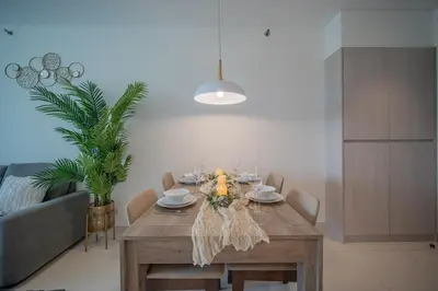 a dining room with a table with chairs and a plant at Cassia 2 BR Lake&Road View apt by NLA in Bang Tao Beach