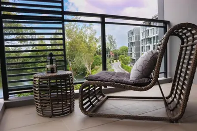 a wicker rocking chair sitting on a balcony with a window at Cassia 2 BR Lake&Road View apt by NLA in Bang Tao Beach