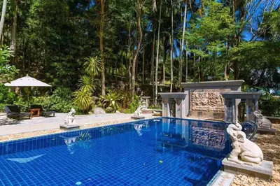 a large swimming pool in a yard with trees at Classic Thai style Cozy Villa fancy pool+garden in Patong Beach