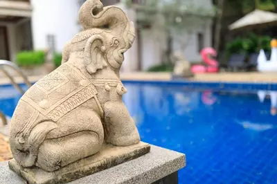 a stone statue sitting next to a swimming pool at Classic Thai style Cozy Villa fancy pool+garden in Patong Beach