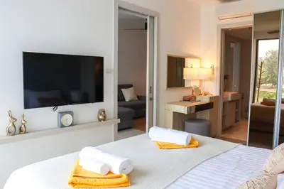 a bedroom with a white bed with a flat screen tv at Cassia 1 BR Lake&Pool View apt by NLA in Bang Tao Beach
