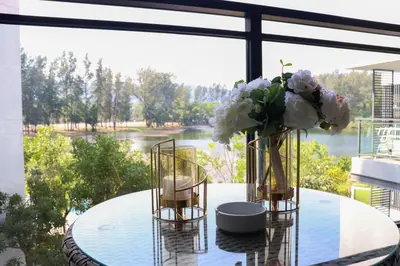 a glass table with a vase of flowers on it at Cassia 1 BR Lake&Pool View apt by NLA in Bang Tao Beach