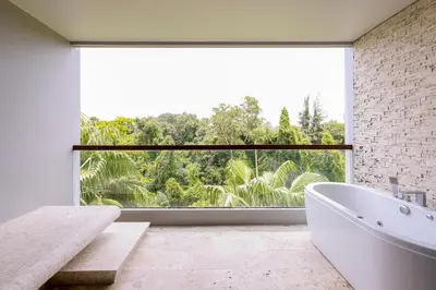 a bathroom with a white tub and a large window at The Regent Bangtao Apartments gorgeous view of the jungle in Bang Tao Beach