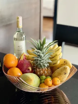 a bowl of fruit on a table with a bottle of wine at The Regent Bangtao Apartments gorgeous view of the jungle in Bang Tao Beach