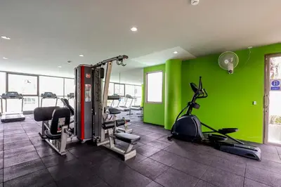 a gym with several tread machines and green walls at The Regent Bangtao Apartments gorgeous view of the jungle in Bang Tao Beach