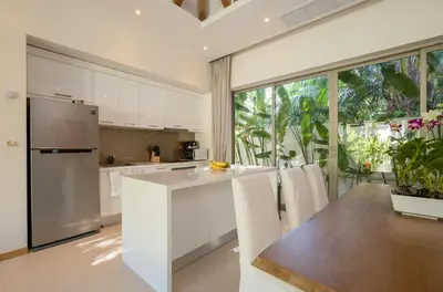 a kitchen with white cabinets and a large window at 3-Bedroom Pool Villa in Trichada Bangtao in Bang Tao Beach