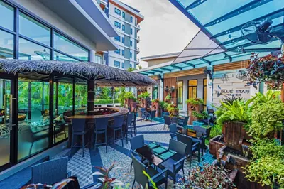 an outdoor patio with chairs and tables and an umbrella at Chalong Miracle Lakeview in Chalong