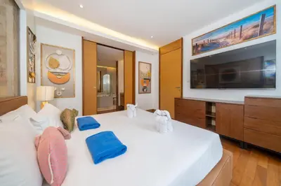 a bedroom with a white bed with a flat screen tv at Naithon beachfront apartment-pool gym restaurant in Nai Thon Beach