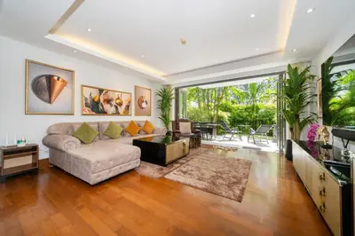 a living room with a couch and a television at Naithon beachfront apartment-pool gym restaurant in Nai Thon Beach