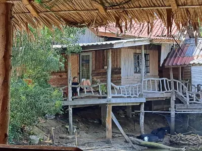 a woman sitting on a porch of a house at Big Hug Home-Nok kao house in Ko Yao Noi