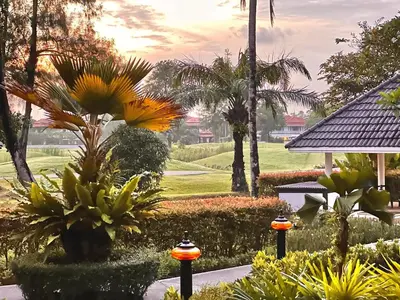 a garden with flowers and palm trees in a resort at Golf View, Allamanda 3 Apartment in Ban Mut Dok Khao