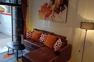 a living room with a brown couch and a table at Naka Tangerine Holiday Home by Bcare in Ban Rangeng