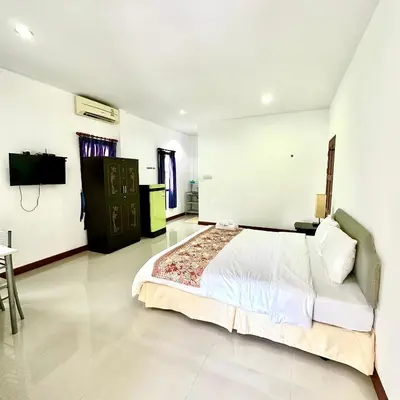 a bedroom with a large bed and a tv in it at Chamil House (ชามิล เฮ้าส์) in Ban Ko En