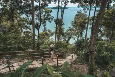 a woman walking down a stairs in a forest with the water at Villa Escape Burasari in Phuket Town