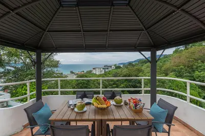 a table and chairs on a balcony with a view of the ocean at 5BR Jungle Seaview Villa Patong in Patong Beach