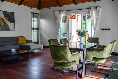 a living room with a glass table and green chairs at Luxurious Residence Rawai in Phuket Town