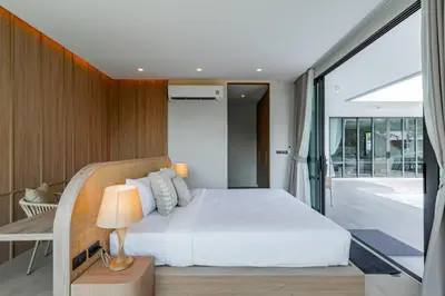 a bedroom with a white bed and a sliding glass door at Aya Residence Garden View in Ban Ket Ho