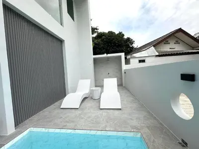 a balcony with two white chairs and a swimming pool at Kata Place Villa in Kata Beach