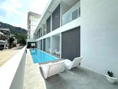 a balcony with white chairs and a swimming pool at Kata Place Villa in Kata Beach