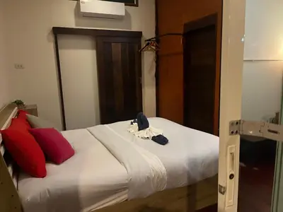 a bedroom with a bed with white sheets and red pillows at Banpoo in Ko Yao Noi