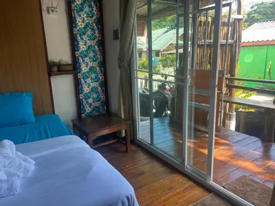 a bedroom with a bed and a door to a balcony at Banpoo in Ko Yao Noi