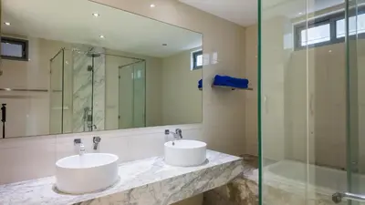 a bathroom with two sinks and a glass shower at The Kata View Phuket apartment in Kata Beach