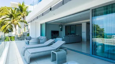 an open living room with blue furniture on the balcony of a house at The Kata View Phuket apartment in Kata Beach