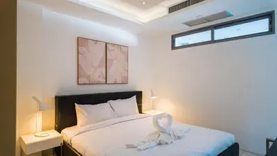 a bedroom with a bed with white sheets and a window at The Kata View Phuket apartment in Kata Beach