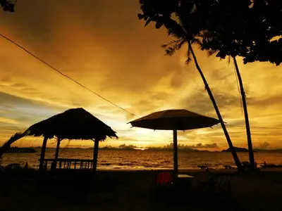 two umbrellas and chairs on the beach at sunset at Swiss Bonihouse Koh Yao Yai in Ban Phlu Nai