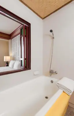 a bathroom with a tub and a mirror and a bed at THE TOP PATONG RESORT. in Patong Beach