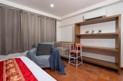 a bedroom with a bed and a crib and a chair at Beachside Apt Short Walk to Nai Harn Beach 2-3 BR in Nai Harn Beach