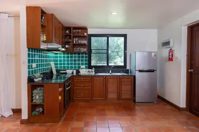 a kitchen with wooden cabinets and a stainless steel refrigerator at Beachside Apt Short Walk to Nai Harn Beach 2-3 BR in Nai Harn Beach