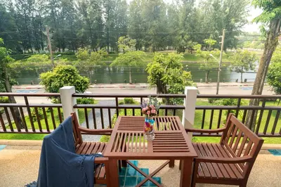 a wooden table and chairs on a balcony with a view at Beachside Apt Short Walk to Nai Harn Beach 2-3 BR in Nai Harn Beach