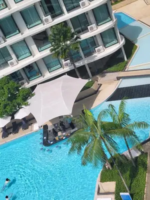an umbrella over a swimming pool in front of a building at La Vita Phuket Rawai in Rawai Beach