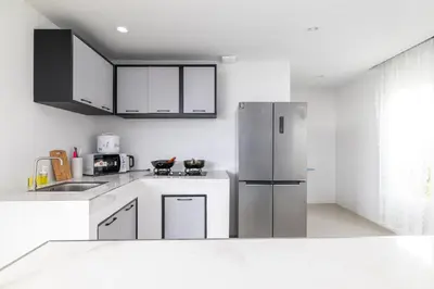 a kitchen with white cabinets and a refrigerator at Andaman Sea Best Pool Access and Villas in Chalong