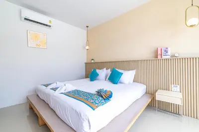 a bedroom with a large white bed with blue pillows at Andaman Sea Best Pool Access and Villas in Chalong