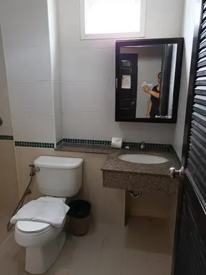 a person taking a picture of a bathroom with a toilet and sink at New Lavender Hotel Patong in Patong Beach