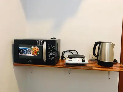 a microwave and a toaster on a wooden shelf at M&N Guesthouse Kata in Kata Beach