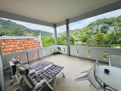 a large room with a balcony with chairs and a table at M&N Guesthouse Kata in Kata Beach