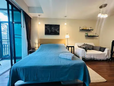 a bedroom with a blue bed and a couch at Brand Naithon Condo C411 in Nai Thon Beach
