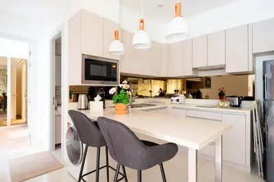 a kitchen with white cabinets and a table and chairs at Cassia Residences by NLA in Bang Tao Beach